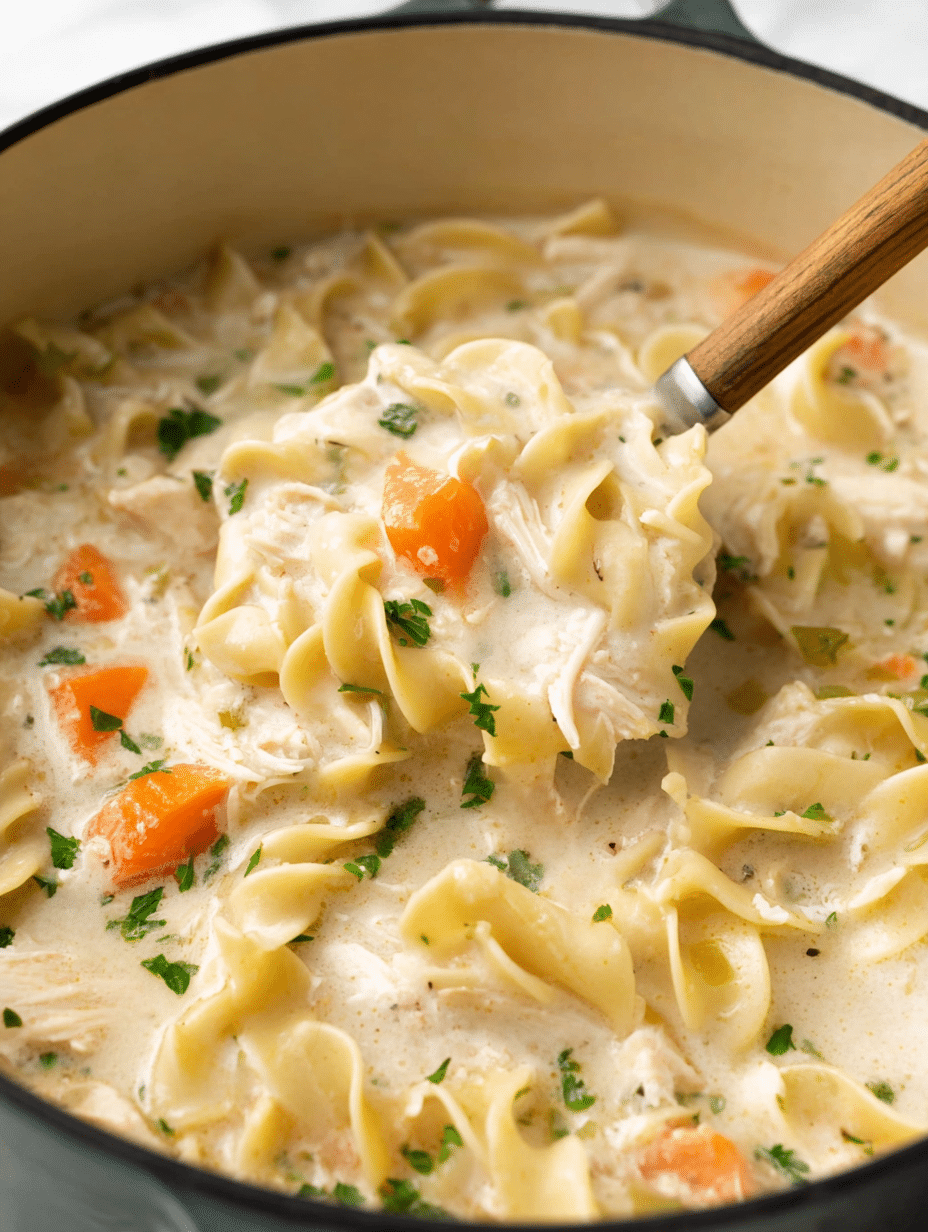 Delicious creamy chicken noodle soup in a bowl, garnished with parsley and served with bread.