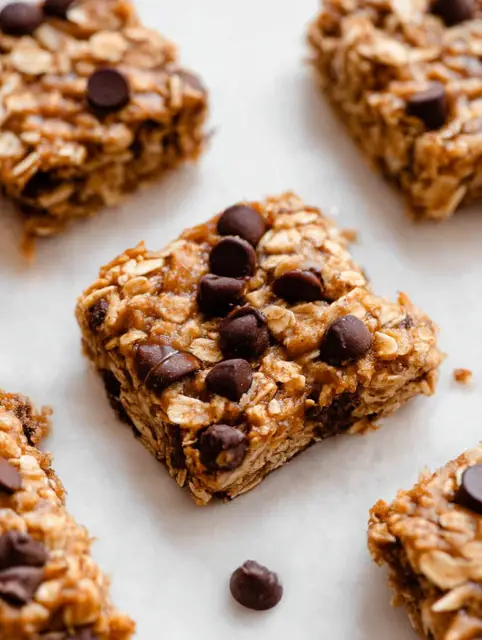 Close-up of banana peanut butter oatmeal bars with chocolate chips on a cutting board.