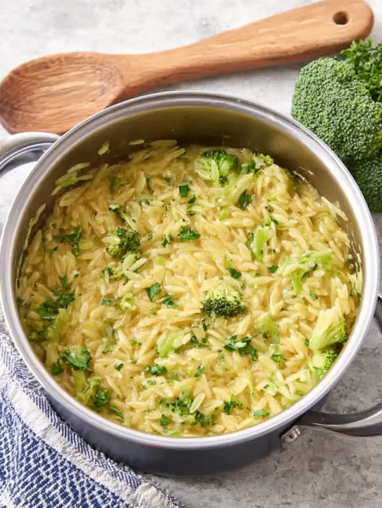 Bowl of creamy broccoli cheddar orzo with fresh garnish, highlighting its rich texture and vibrant colors.