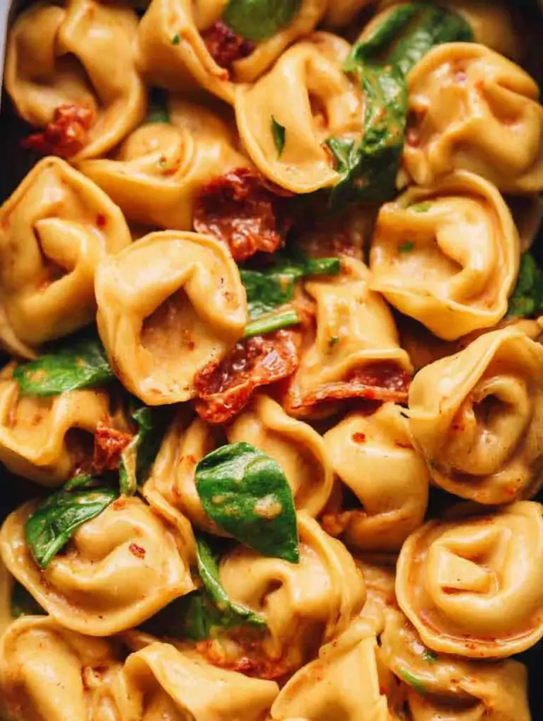 Creamy Marry Me Tortellini in a bowl, garnished with fresh spinach and Parmigiano cheese.