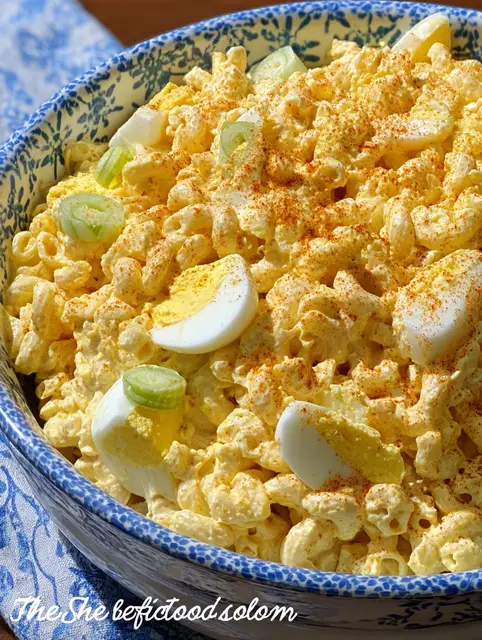 Deviled egg macaroni salad served in a bowl with garnishes, perfect for a summer picnic.