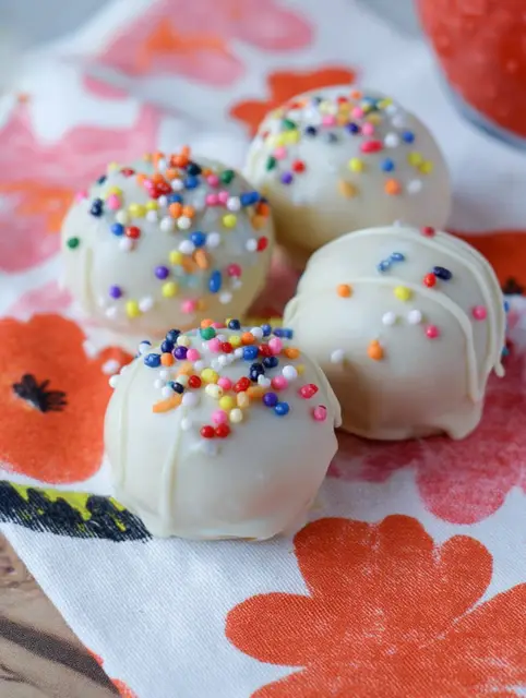 No-bake cake batter truffles with chocolate drizzle and sprinkles on a plate
