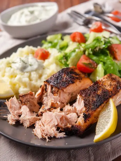 Plated Texas Roadhouse salmon served with garlic butter sauce and fresh lemon wedges.