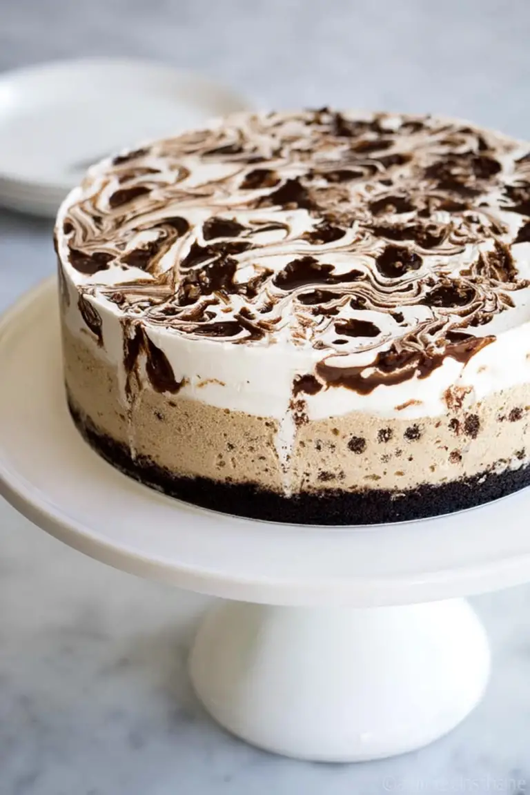 Slice of coffee ice cream cake with brownie bottom and vanilla fudge swirl, served on a plate