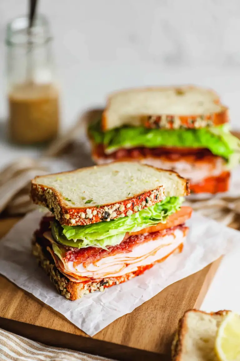 Close-up of an easy turkey club sandwich with layers of turkey, bacon, and avocado on a wooden board.