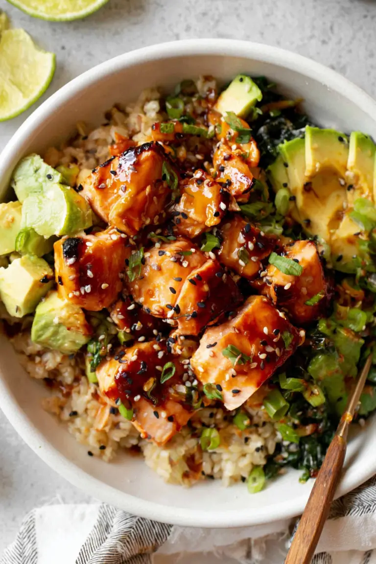 Honey glazed salmon rice bowl with avocado and cucumber on a rustic table.