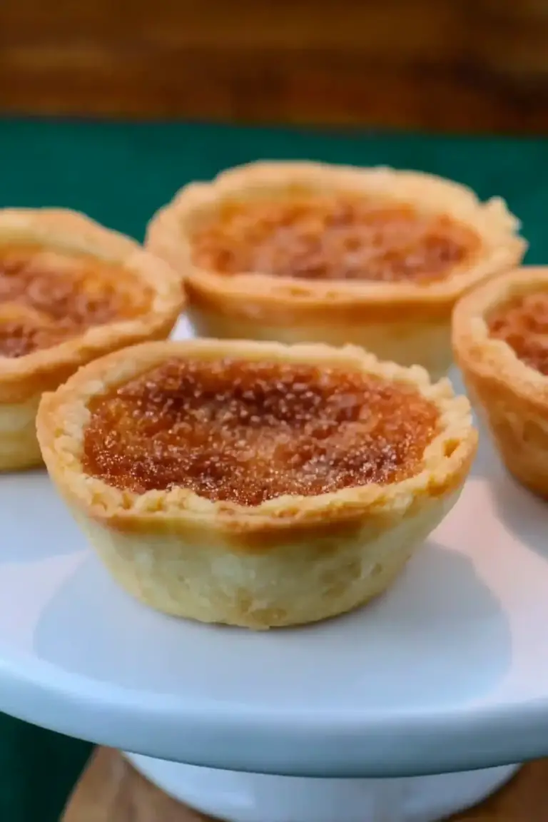 Delicious homemade old fashioned butter tarts with a golden crust and rich filling, served on a rustic wooden table.
