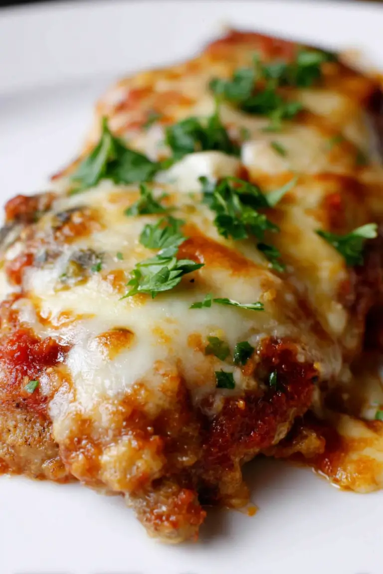 Delicious veal parmigiana with melted mozzarella and fresh parsley on top, served with a side of pasta.