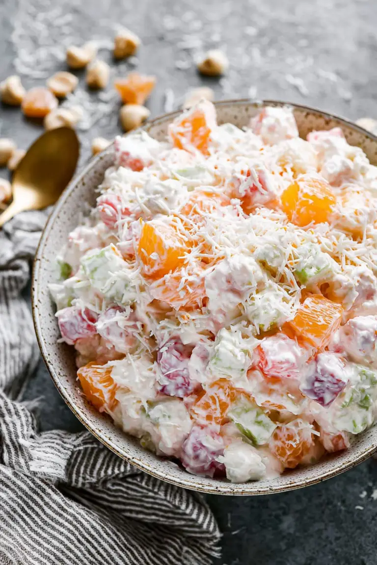 Delicious ambrosia fruit salad in a decorative bowl, showcasing a mix of pineapple, mandarin oranges, cherries, and mini marshmallows.