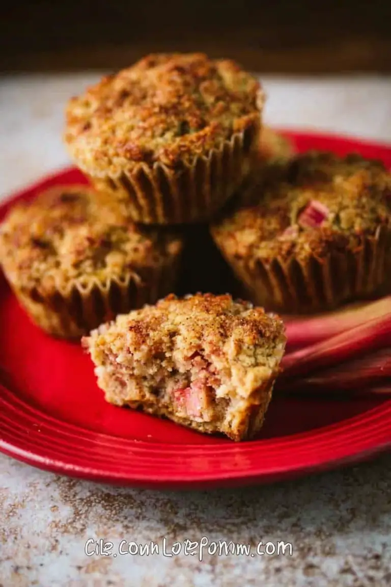 Freshly baked gluten-free cinnamon rhubarb muffins with rhubarb stalks and cinnamon on a wooden table.