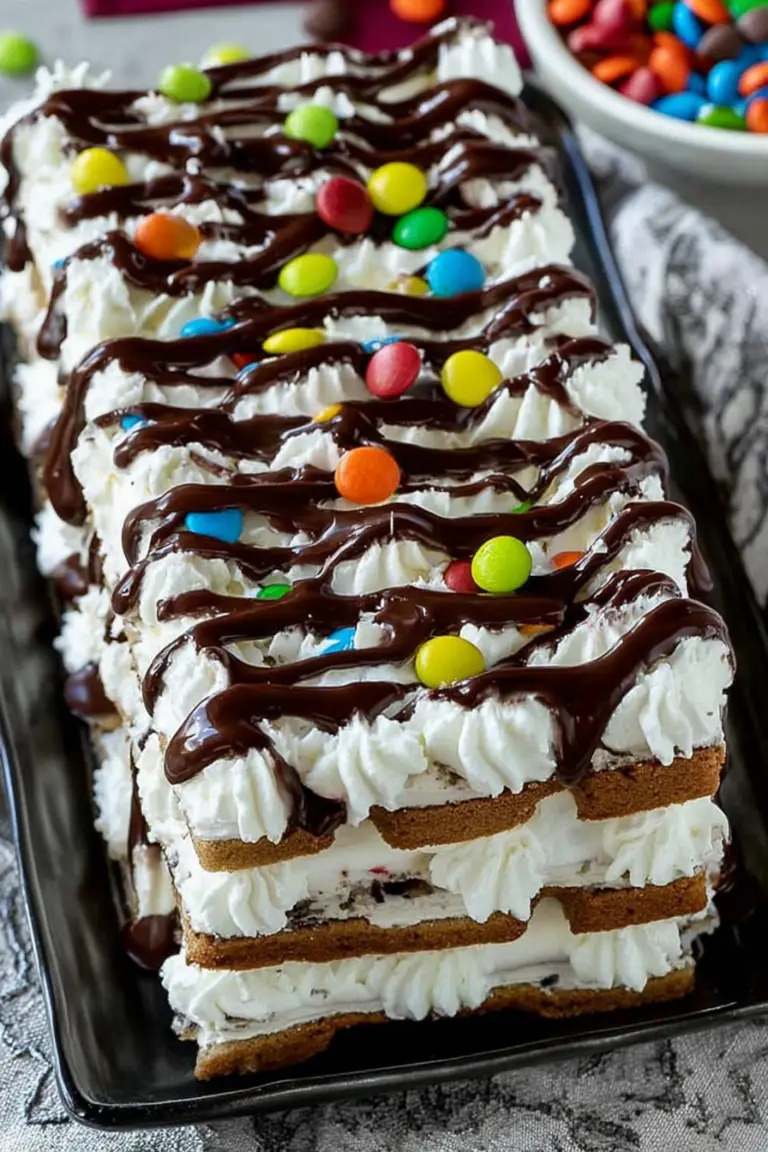 Colorful ice cream sandwich cake layered with whipped topping and candy, perfect for summer gatherings.