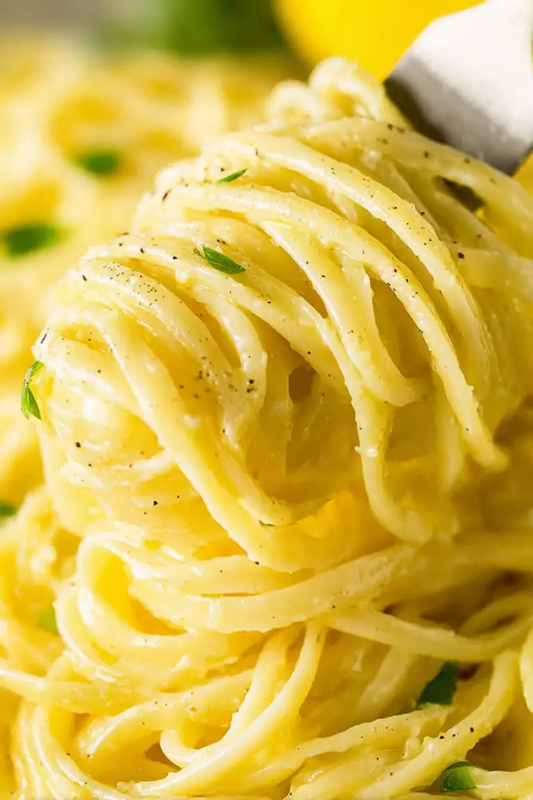 Close-up of creamy lemon pasta in a bowl garnished with parsley and lemon slices.