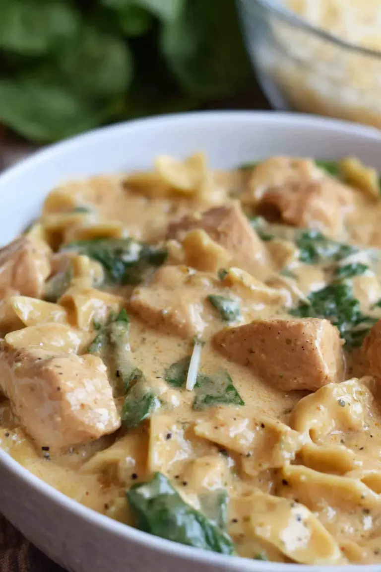 Delicious dairy free chicken alfredo with spinach and dairy free parmesan served on a wooden table.