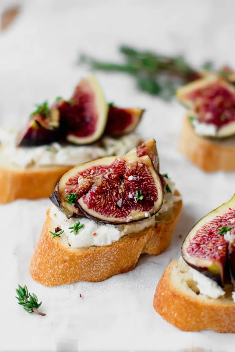 Delicious fig and goat cheese crostini served on a rustic wooden table with thyme and honey.