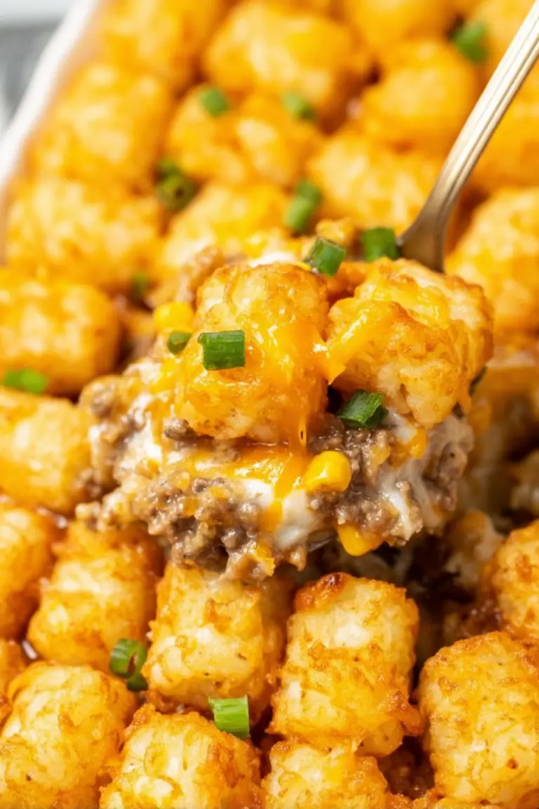 Golden-brown tater tot casserole topped with scallions on a wooden table.