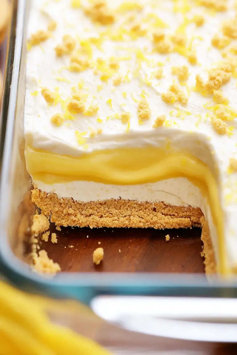 Slice of Heavenly Lemon Oreo Dessert garnished with lemon zest and mint on a white plate.