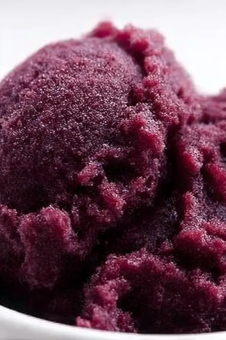 Delicious mulberry and blackberry sorbet served in a bowl with fresh mint leaves and berries.