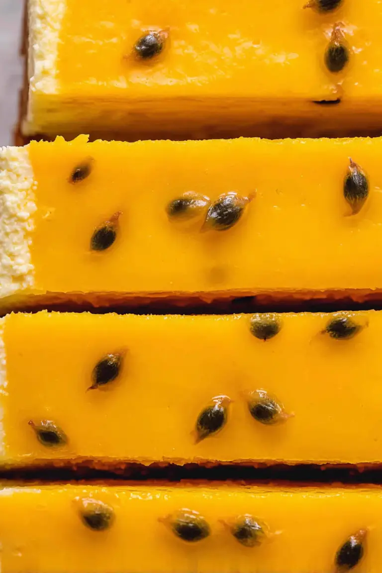 Slice of no-bake passion fruit cheesecake with fresh passion fruit seeds and mint garnish on a plate.