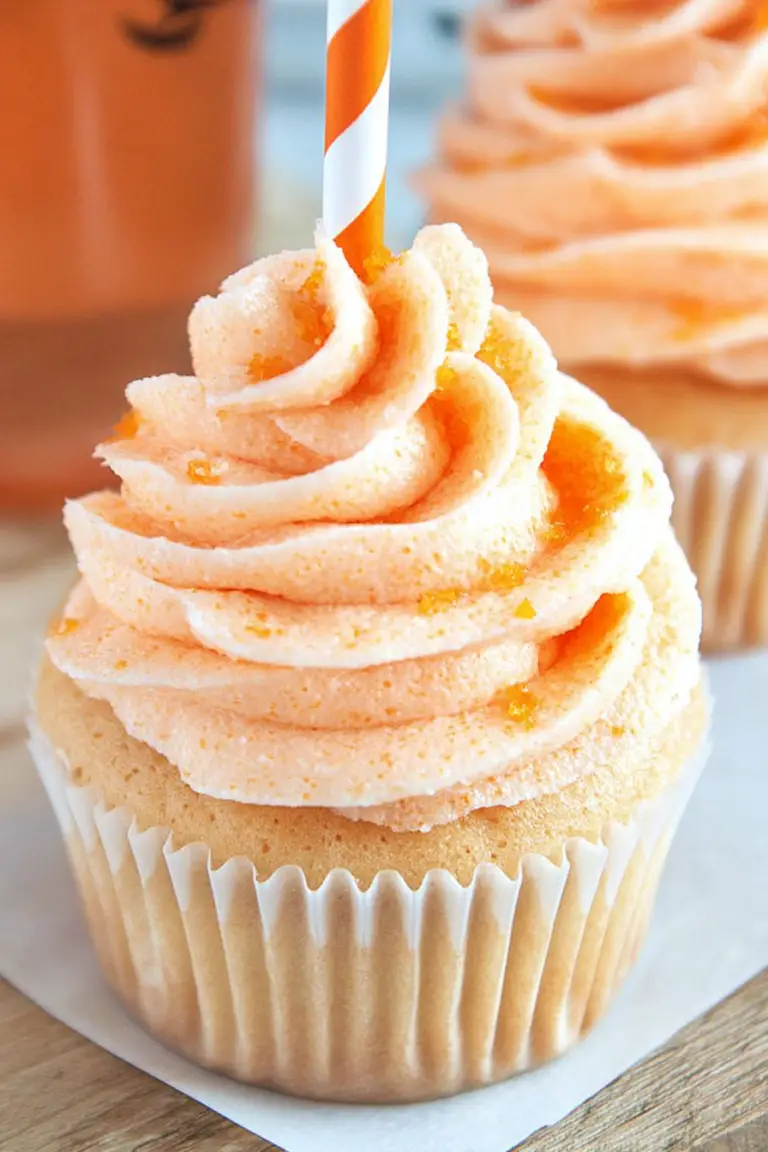 Colorful orange creamsicle cupcakes with orange buttercream and orange slices on top.