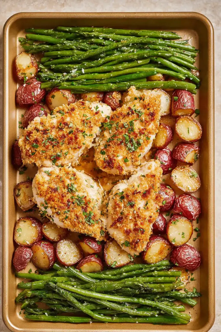 Delicious parmesan crusted chicken with roasted potatoes and green beans on a wooden table.