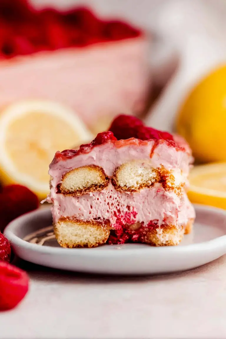 Close-up of raspberry tiramisu garnished with fresh raspberries and lemon slices, showcasing the creamy layers.