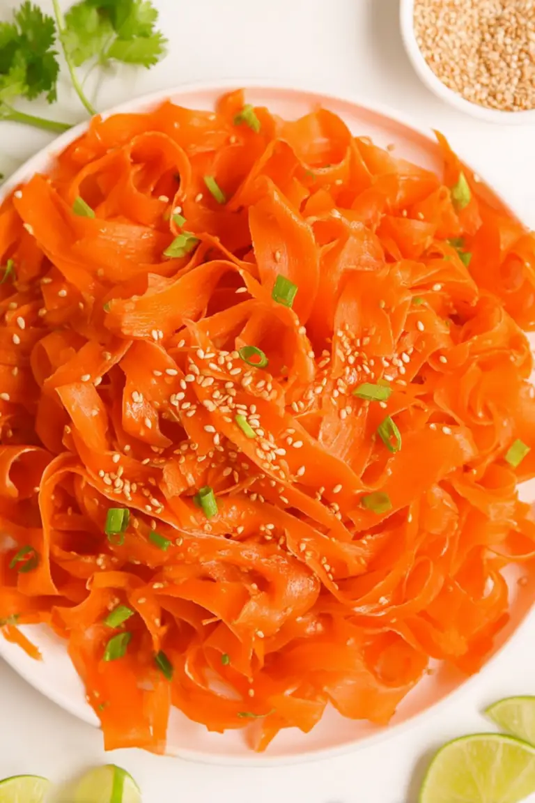 Vibrant raw carrot salad with sesame seeds and green onions in a wooden bowl