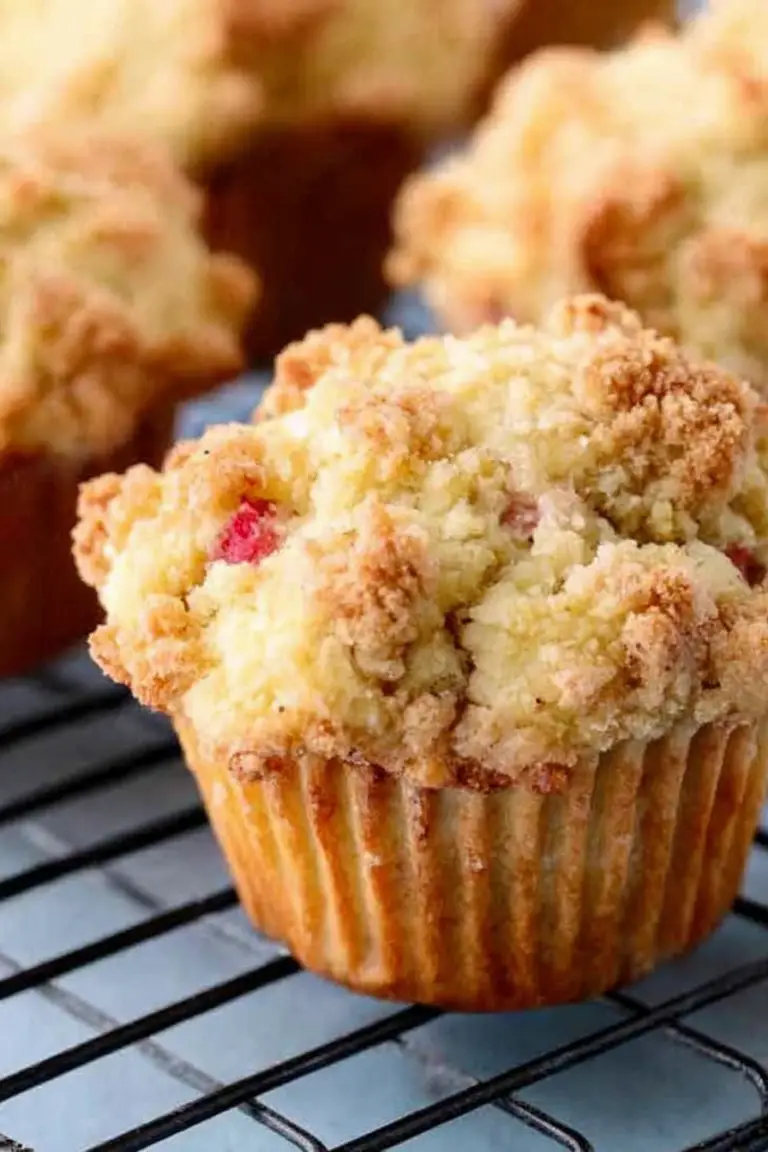 Freshly baked rhubarb streusel muffins on a rustic table with rhubarb stalks.