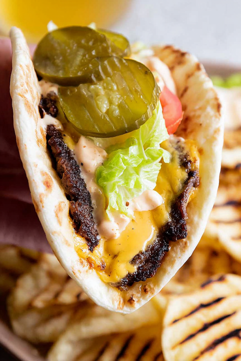 Flat lay of delicious smash burger tacos with lettuce, pickles, and burger sauce on a wooden board.