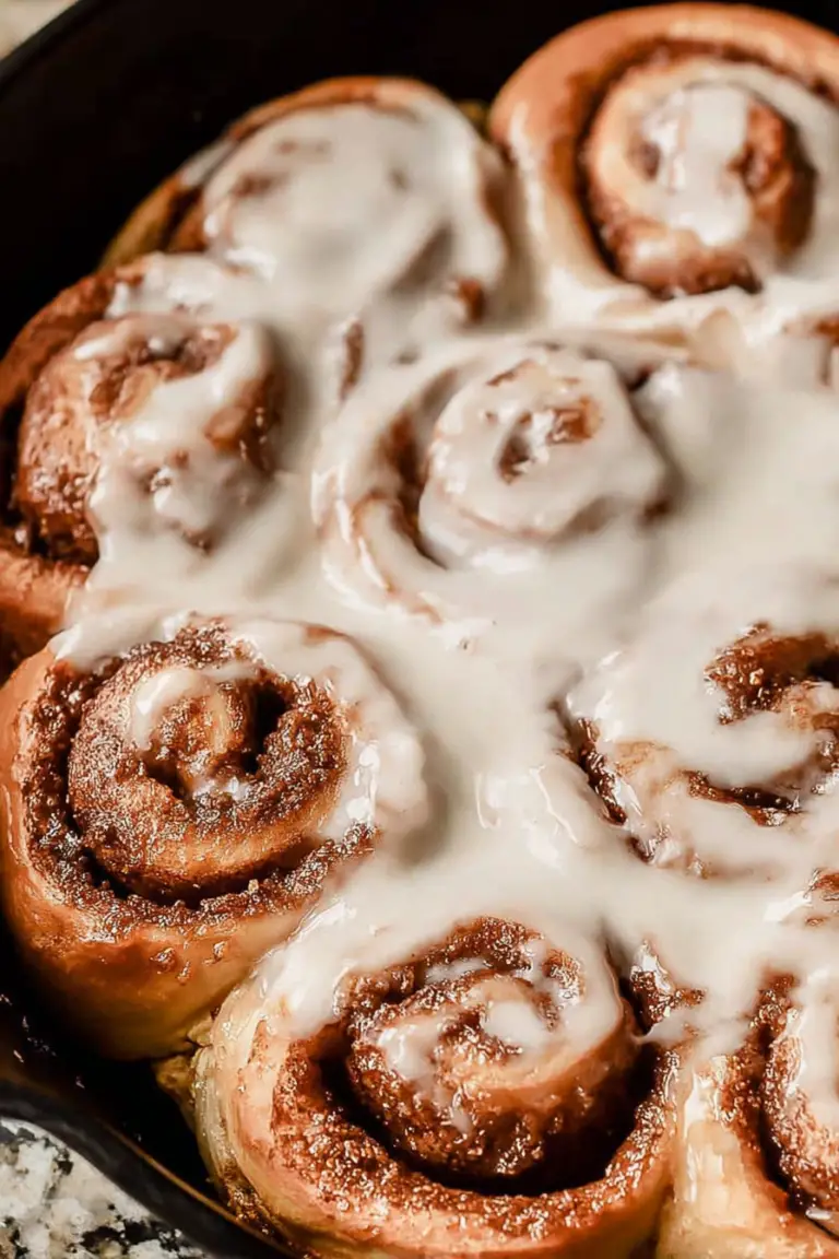 Freshly baked fluffy sourdough cinnamon rolls drizzled with glaze on a wooden table