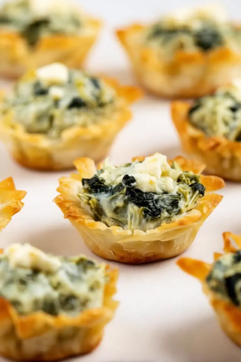 Close-up of golden brown spinach artichoke bites on a decorative plate, garnished with fresh herbs.