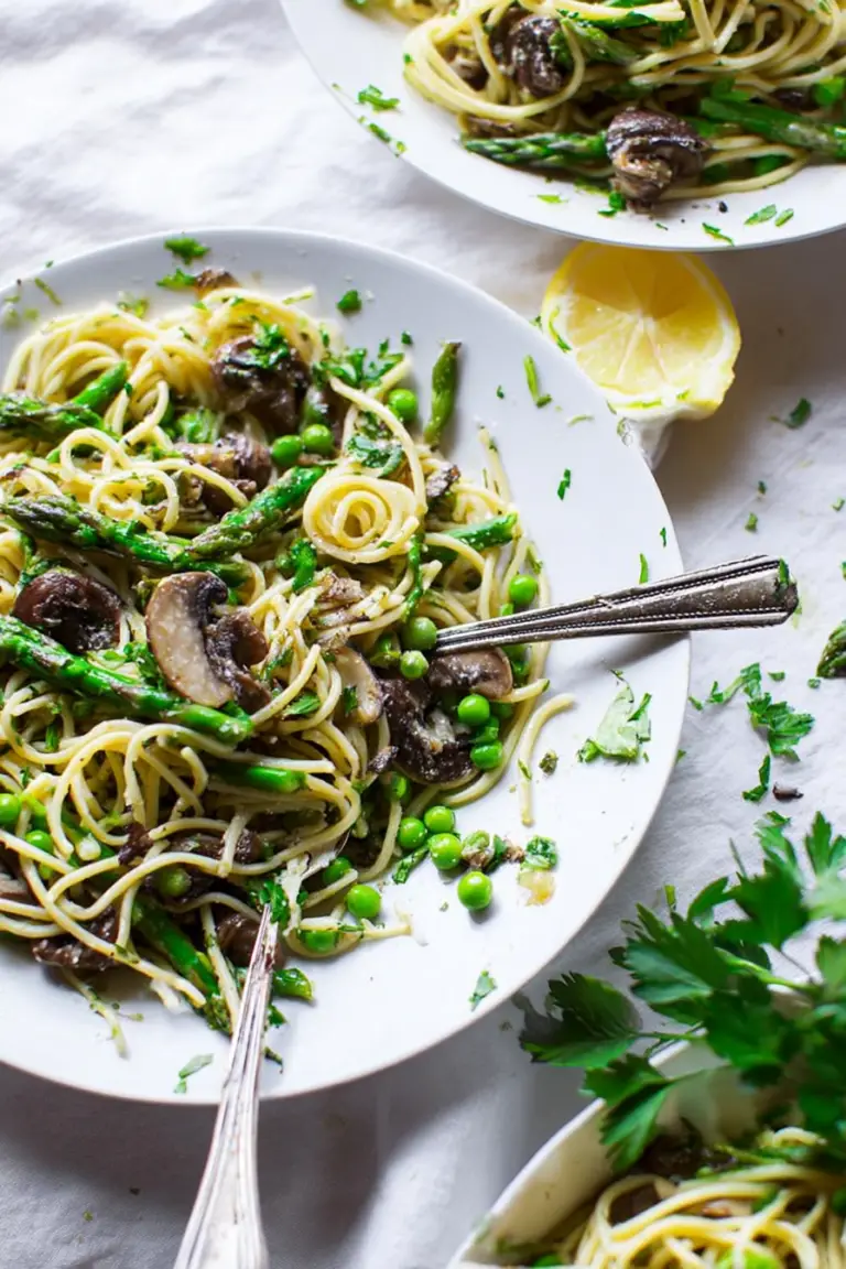 Fresh spring pasta salad with asparagus and mushrooms in a bowl, topped with chopped herbs