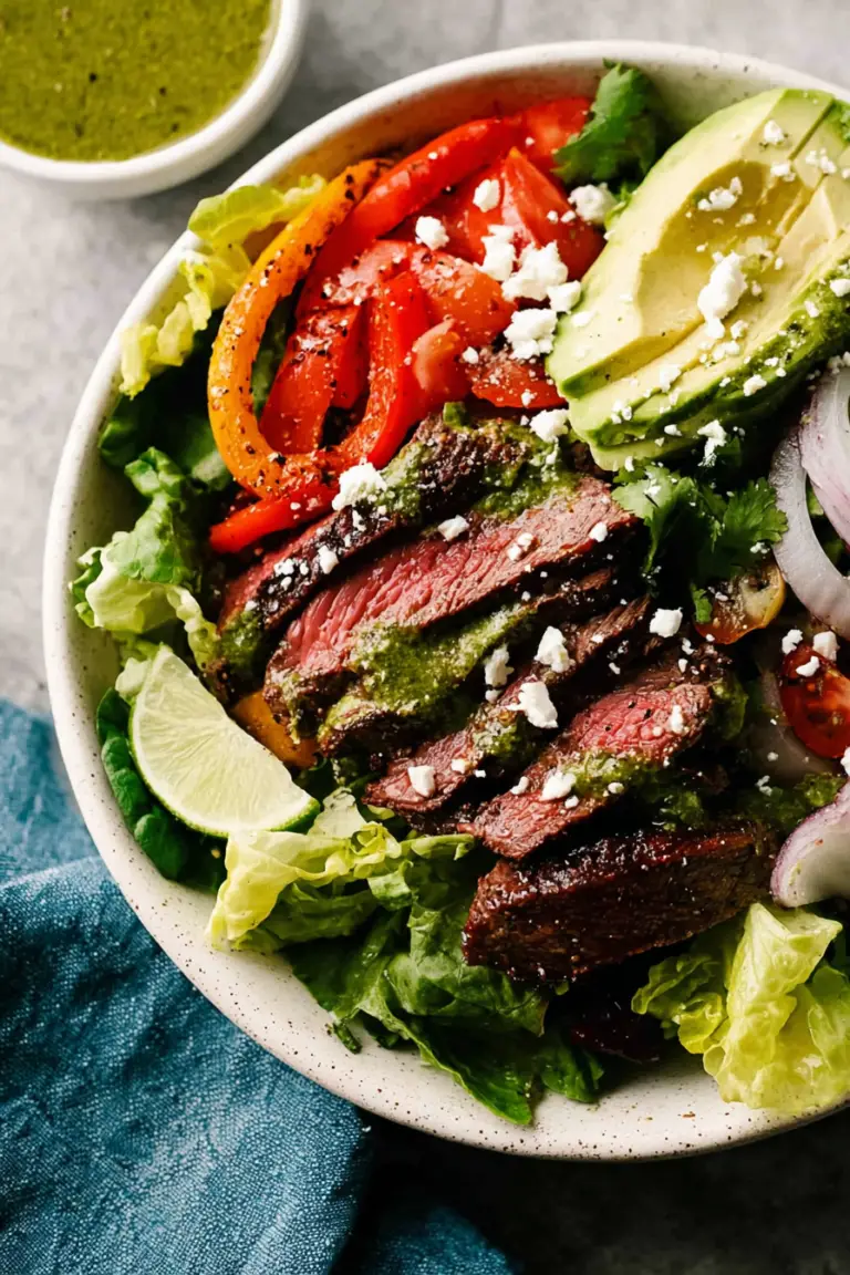 Close-up of a steak fajita salad topped with colorful vegetables and cilantro lime dressing.