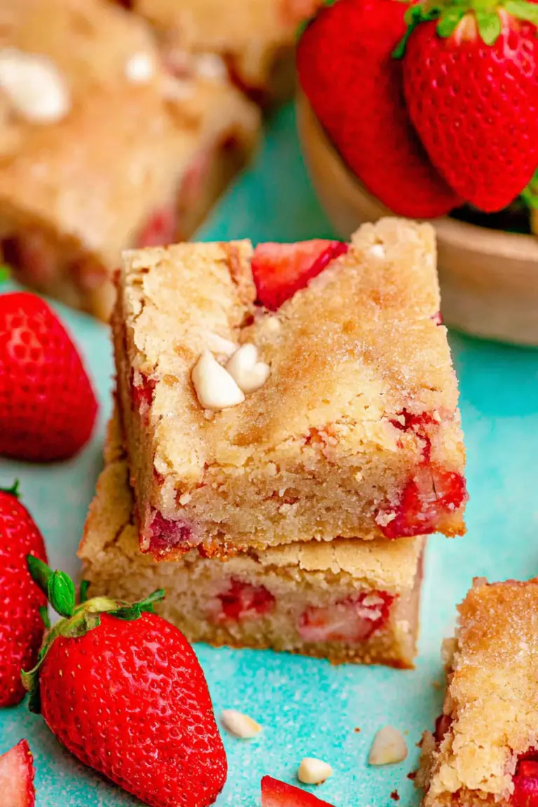 Close-up of strawberry white chocolate blondies with fresh strawberries on a wooden table.