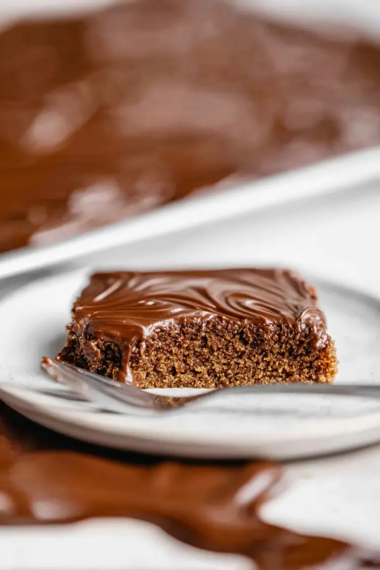 Delicious Texas sheet cake with buttermilk topped with chocolate frosting, displayed in a baking pan with a slice cut out to reveal moist interior.
