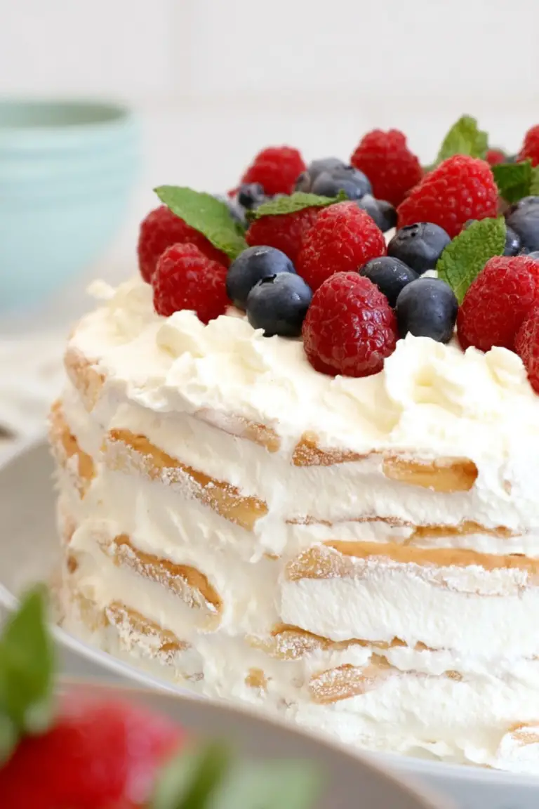 Slice of vanilla wafer icebox cake on a plate with fresh strawberries and blueberries.