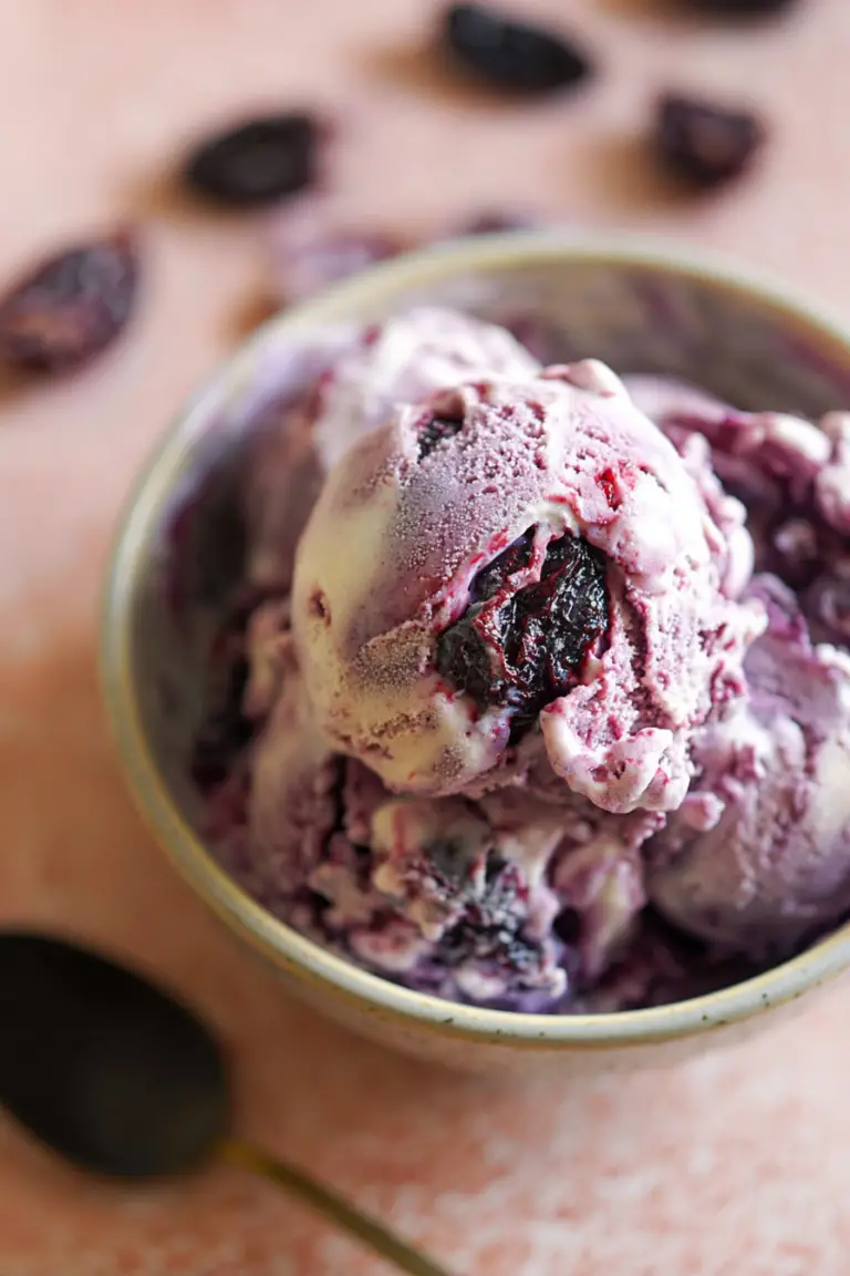 Vegan mulberry ice cream in a bowl, decorated with fresh mulberries and mint leaves.