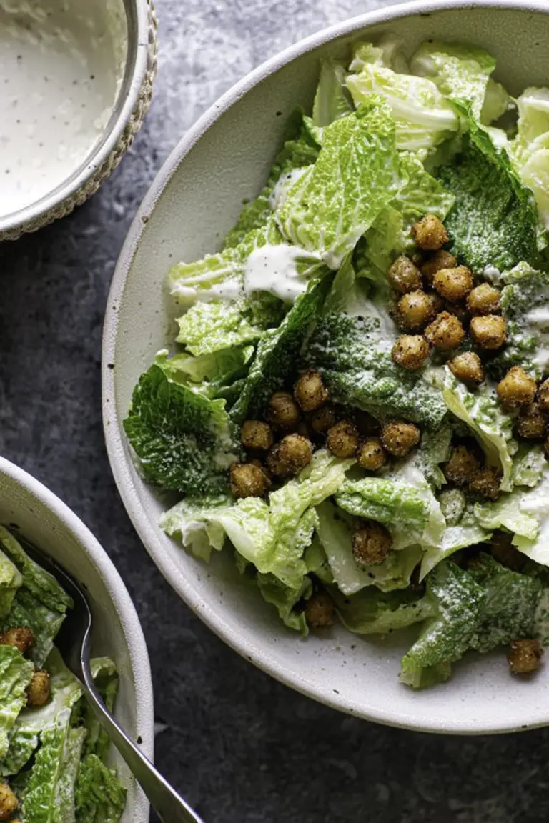 Vegan romaine Caesar salad with crispy chickpea croutons and dressing on a wooden table.
