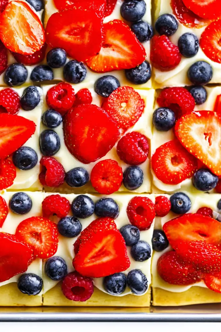 Delicious fruit pizza with fresh strawberries, blueberries, and kiwi on a wooden table.