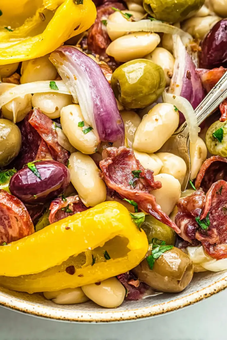Delicious white bean antipasto salad filled with olives, artichokes, and colorful vegetables served in a rustic bowl.