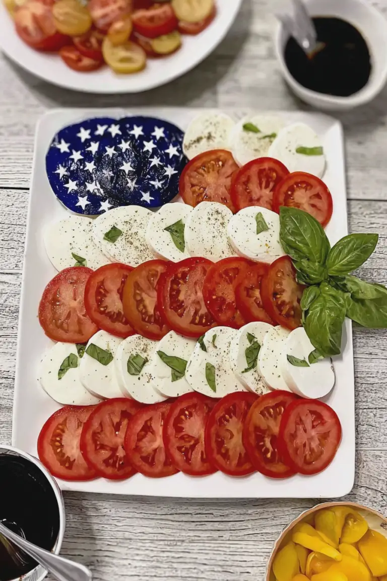 Patriotic American Flag Caprese Salad featuring layers of tomatoes, mozzarella, and blueberries on a wooden table.