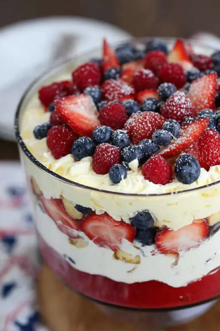 Vibrant angel food berry trifle with layers of strawberries, blueberries, and raspberries in a glass bowl.