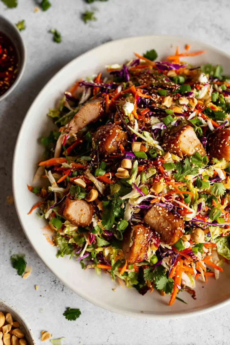 Delicious Asian Chicken Crunch Salad with purple and green cabbage, sliced bell peppers, and sesame seeds presented in a bowl.