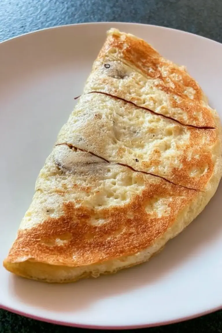 Delicious banana omelette garnished with banana slices and chili flakes on a rustic table with coffee.