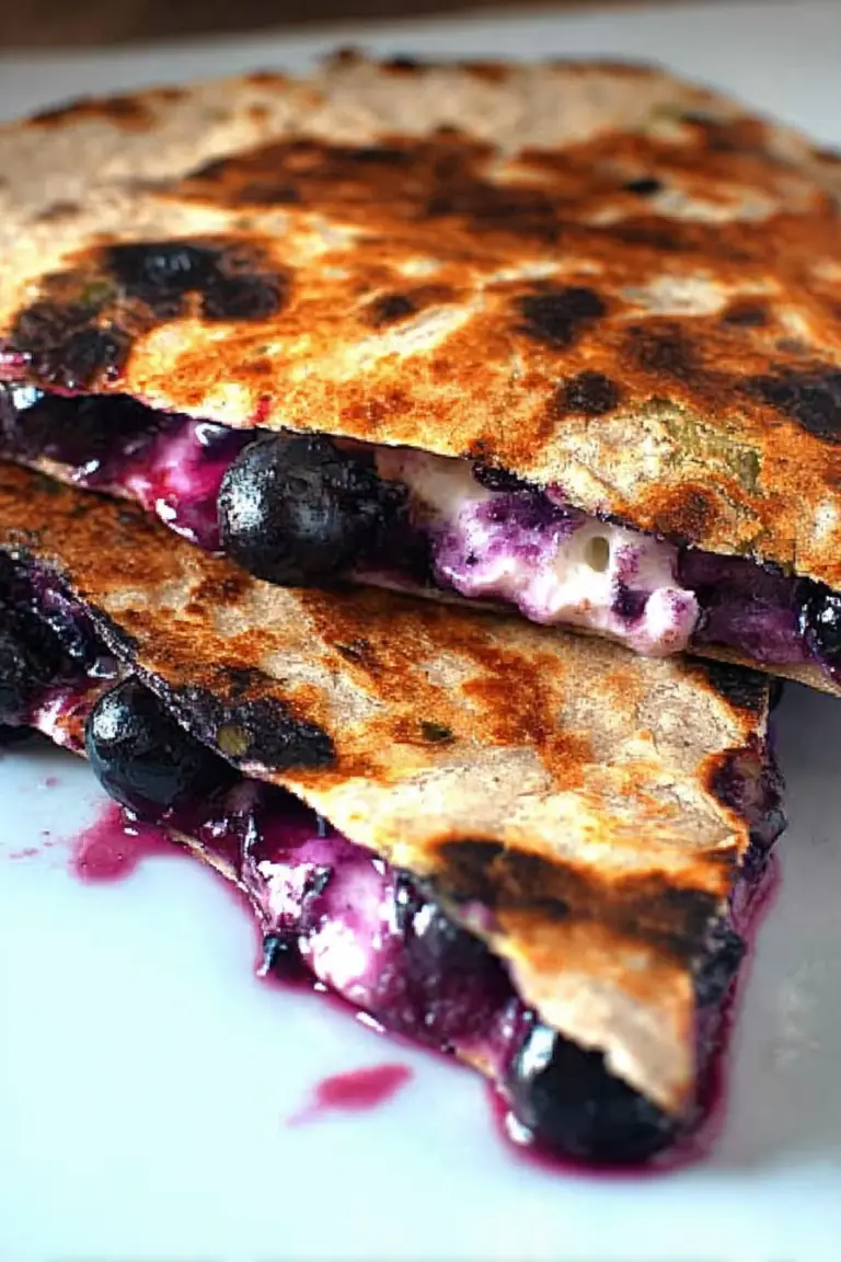 Delicious blueberry breakfast quesadilla served on a white plate with fresh blueberries and whipped cream.