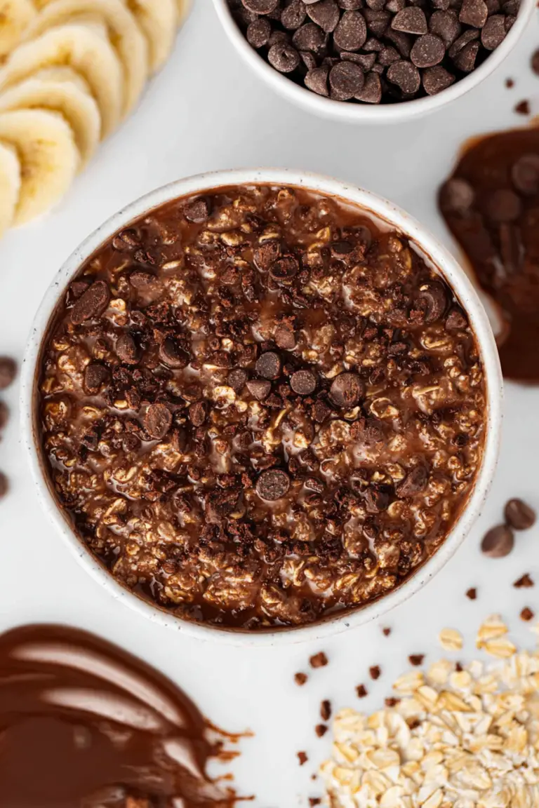 Delicious chocolate oatmeal topped with fresh strawberries and walnuts in a wooden bowl.