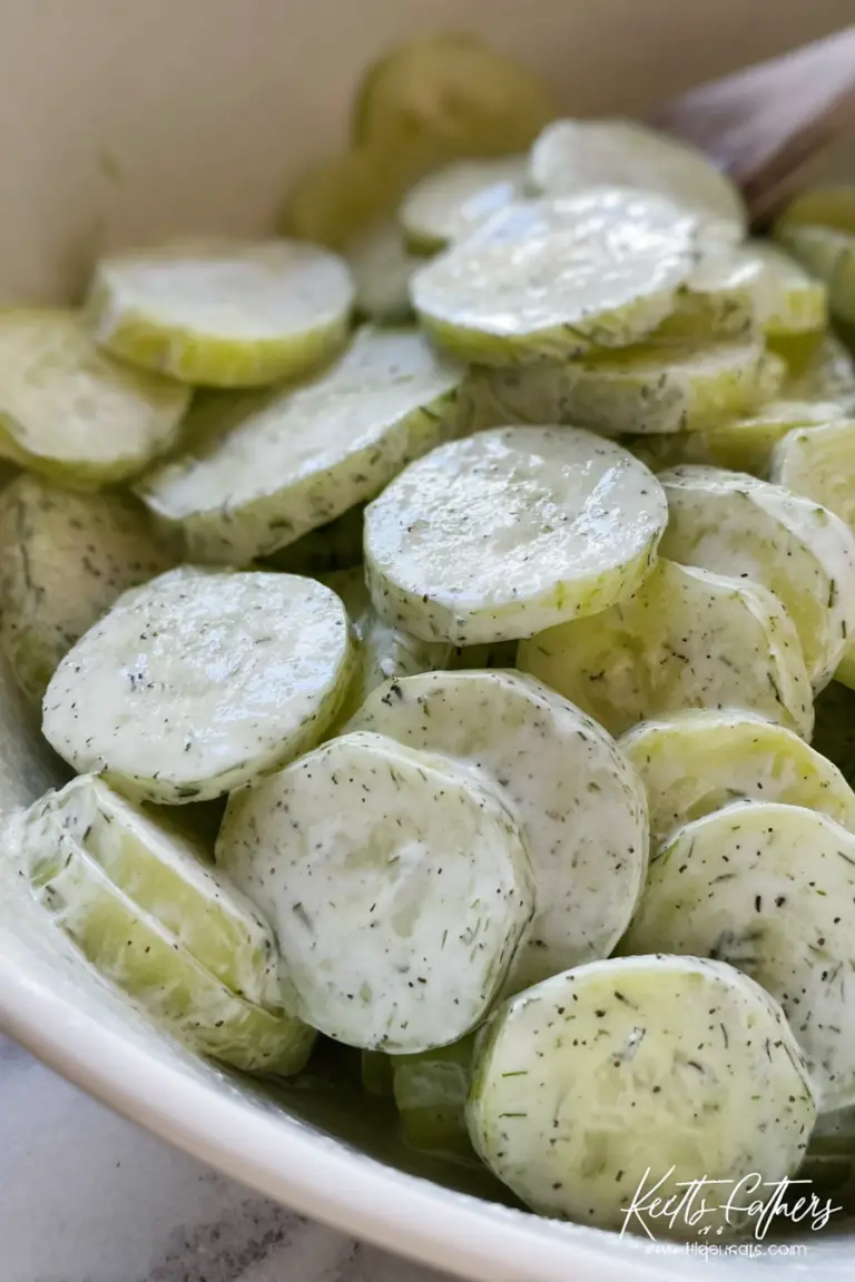 Creamy cucumber salad in a bowl with fresh dill, served on a wooden table.