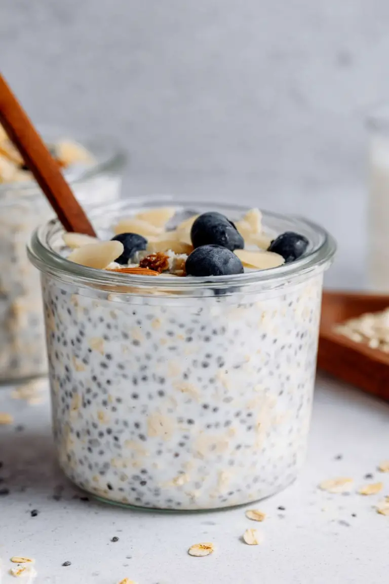 Bowl of creamy vanilla overnight oats with fresh berries and granola on a wooden table.