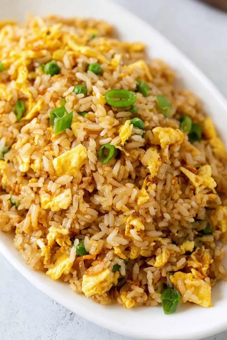 Delicious egg fried rice served on a plate with green onions, ready to enjoy.