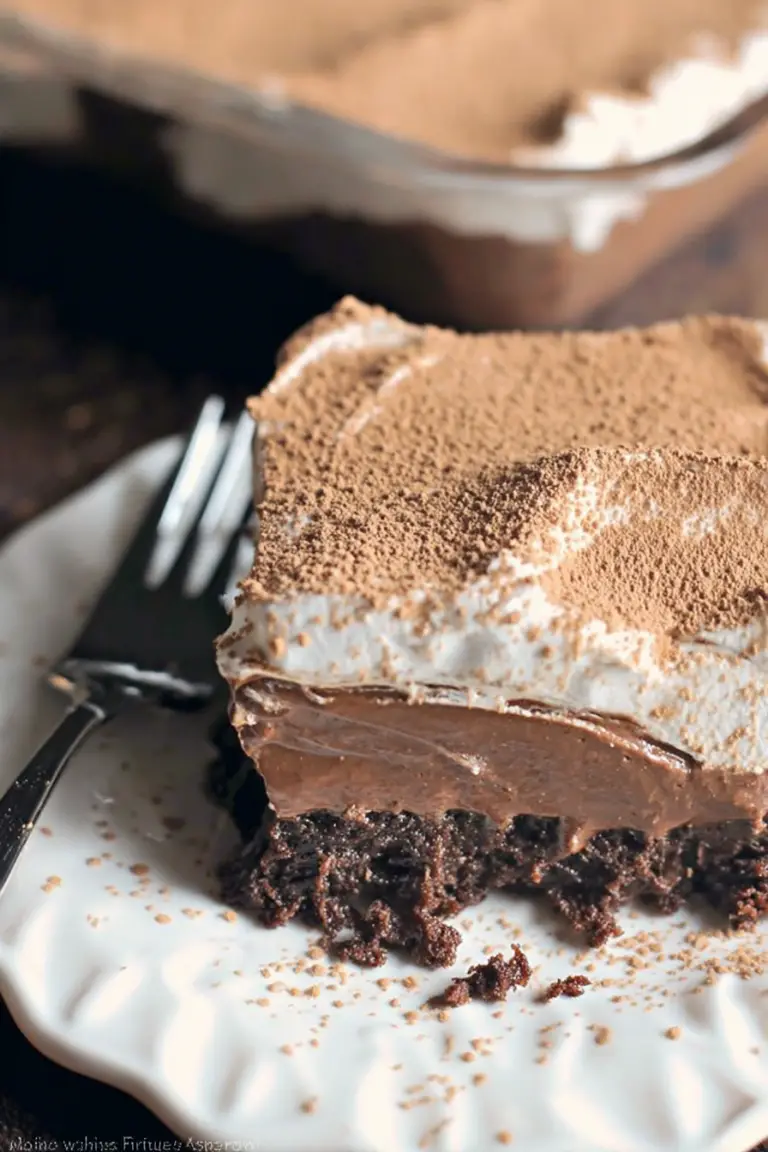 Delicious French silk brownies with a chocolate topping and cool whip, served in a square glass dish.