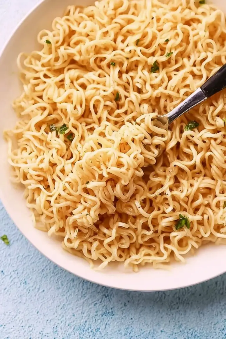Close-up of garlic butter ramen noodles in a white bowl with parsley and chopsticks.
